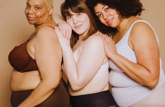 Three overweight women holding each other and smiling, supporting one another on a weight loss journey